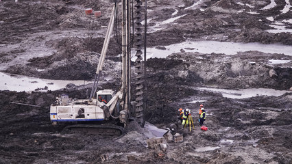 Workers in the mud of a construction site at the stage of excavation; construction of a supermarket AUCHAN