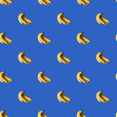 Seamless trendy blue background with ripe bananas. Tropical background with summer fruits, graphic print.