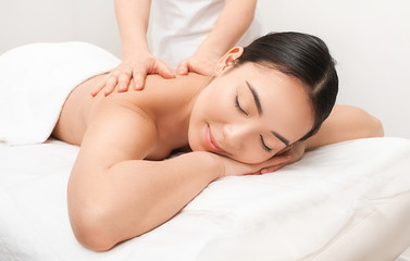 Fototapeta na wymiar Anti-stress Thai massage. A beautiful Asian woman is getting a back massage at a Thai spa resort