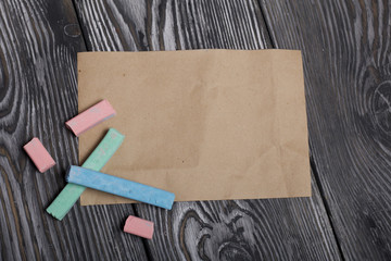 Pieces of chalk for drawing, different colors. Paper. They lie on pine boards painted with white and black paint.
