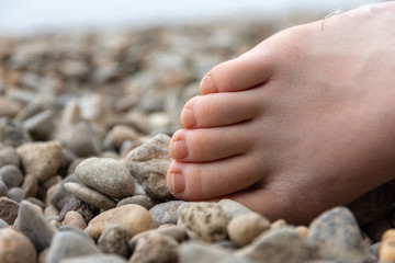Partial view of a human bare foot on pebbles