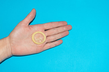 .Unpacked condom on a female palm closeup. Yellow, latex condom on the female hand, a remedy for...