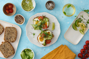 Smashed avocado on whole-grain toast to make avocado and tomato, egg sandwiches.