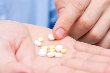 Pills in hand, a man's hand and a Handful of different drugs, close-up, cropped image