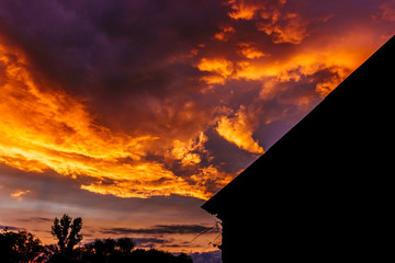 Sunset on the background of a house dark silhouette on a summer evening in the village
