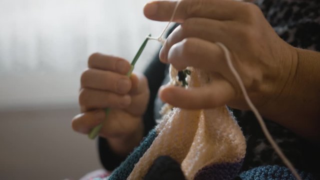 Senior woman handmade bricklaying. She's sewing a cute blanket to her son or granddaughter.