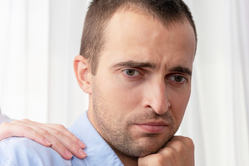 Obraz premium Man is sad, wife puts her hand on man's shoulder, close up