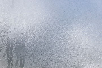 Raindrops on a transparent window pane. Condensate. Gray rainy day. Abstract background