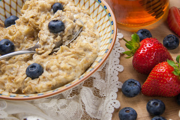 Healthy breakfast - porridge oatmeal with blueberries and strawberries, vegan and gluten free, organic home made meal.