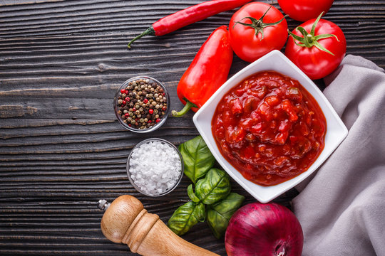 Fresh tasty tomato sauce on rustic wooden background