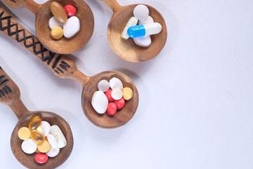 Fototapeta na wymiar Top view of pills and capsule on spoon on white 