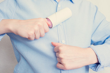 Woman cleaning the shirt with adhesive sticky roller, close up