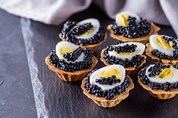 delicious snack tartlets on dark stone background