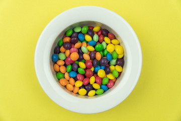 White plate on a yellow background full of multi-colored sweets