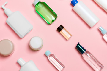 Top view of different cosmetic bottles and container for cosmetics on pink background. Flat lay composition with copy space