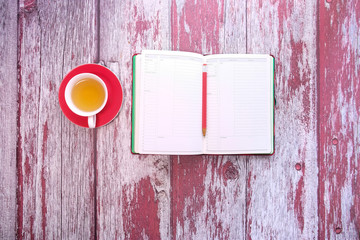 Top view of planner with pen and tea on wooden table 