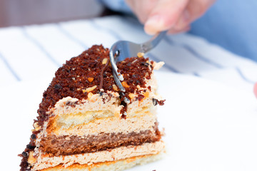 Person breakfast in a cafe with a coffee cake, man's hand, close up