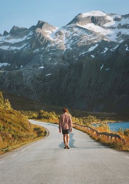 Man walking on the road enjoying mountains view solo travel vacations hitchhiking in Norway outdoor healthy lifestyle summer trip