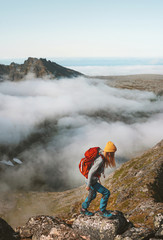 Woman traveler hiking with backpack above clouds travel outdoor climbing adventure vacation active healthy lifestyle extreme sports summer activity in Norway