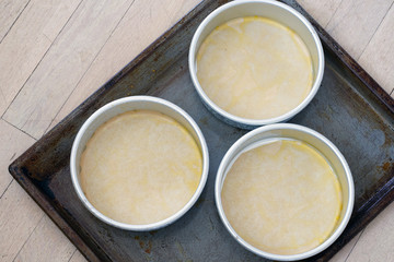 Lining up cake molds with parchment paper on a baking sheet