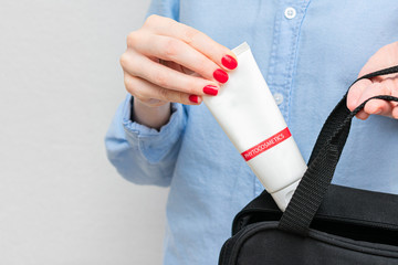 Woman puts packaging of the hand cream in women's bag, women's hands, cropped image