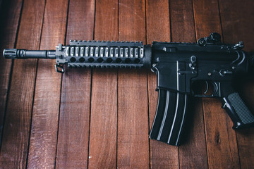 airsoft rifle black on wooden background brown