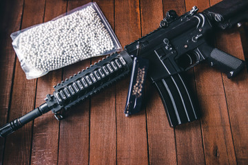 on a wooden table airsoft rifle with the package loader and balls lie