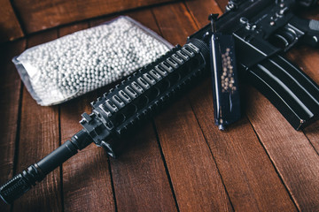loader airsoft rifle and a black bag with balloons lying on background with boards