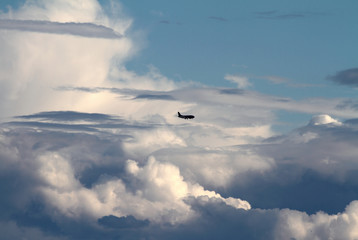 The plane is flying in large white clouds on the horizon