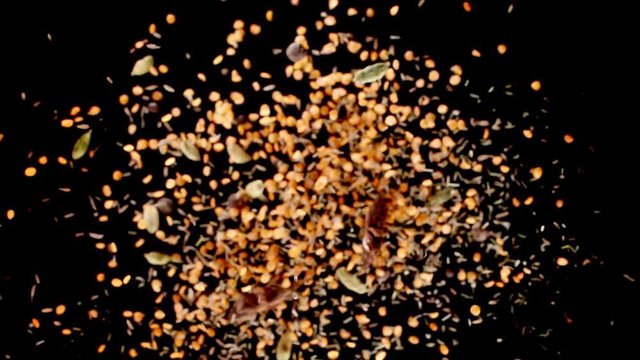 Lentil, star anise, pepper and cumin exploding on black background. Slow motion