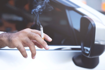 close up man hand hold smoking a cigarette in car while driving travel. healthy lifestyle. or No smoking campaign Concept.