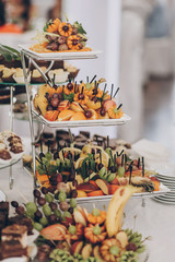 Delicious fresh fruits on stand on table at wedding reception in restaurant. Luxury catering service. Wedding healthy fruit bar. Banana, oranges,grapes,peach, and apples