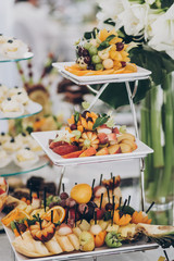 Delicious fresh fruits on stand on table at wedding reception in restaurant. Luxury catering service. Wedding healthy fruit bar. Banana, oranges,grapes,peach, and apples