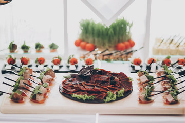 Delicious appetizer and canape on table at wedding reception in restaurant. Luxury catering service. Italian delicatessen, prosciutto snacks, cheese and olives. Christmas feast