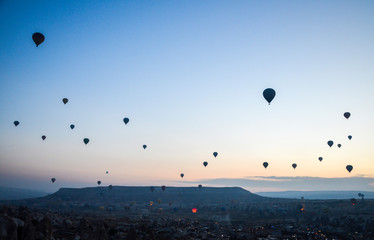 Hot air balloons at sunrise flying in the sky along valleys at Cappadocia of Goreme, Turkey 