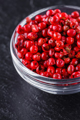 pink peppercorns on a dark stone background