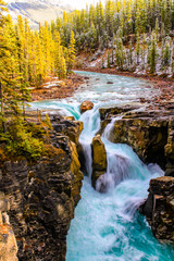 Large boulder stands in the way of water rushing over the Sumwapta Falls. Yoho National Park,...