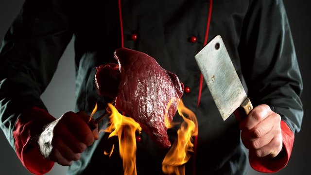 Super slow motion of closeup of chef with cleaver and steak above fire. Filmed on high speed cinema camera, 1000 fps.