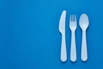 Plastic blue cutlery set with blue background. Top view