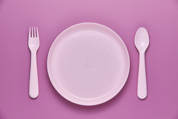 Plastic purple cutlery set with purple background. Top view