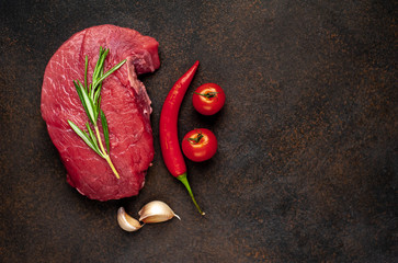 
raw beef steak with spices on a stone background with copy space for your text