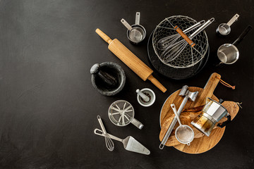 Kitchen utensils (cooking tools) on black background, free copy space