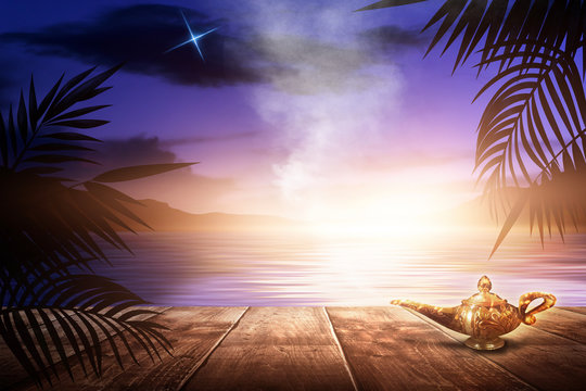 Aladin's lamp on the background of a sea evening landscape with sunset. Palm tree branches, silhouettes, sunlight. Wooden table. Night view, open-air seascape. 3D illustration