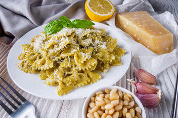 Delicious farfalle pasta with pesto sauce on wooden rustic background