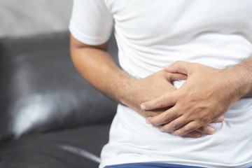 Monochrome black and white image unhappy people man stand sick suffering from stomach ache Focus color red on the abdomen area to show pain.  concept healthcare and health problem.