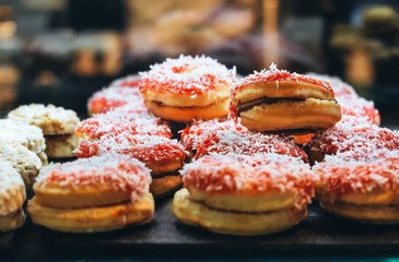 Close-up of a tray of chocolate-filled butter pastries with strawberry and coconut jam topping. Unhealthy eating concept