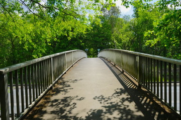 Fototapeta na wymiar Brücke, Fussgängerbrücke mit Geländer führt über Straße, Autobahn, Kraftfahrstraße in die Natur / Wald 