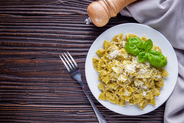 Delicious farfalle pasta with pesto sauce on wooden rustic background