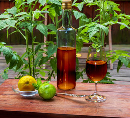 Working from home with a young cognac in a glass, vertical bottle, lemon, and lime on a wooden table