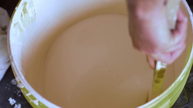 preparing tempera - mixing the paint in the bucket using a stick